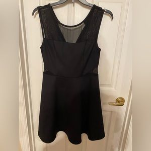 Women’s fit and flare black dress with sheer waist and shoulder panels. Size 14